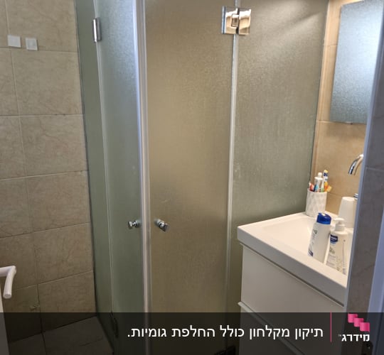 מקלחון זכוכית עם דלתות מתכת בחדר אמבטיה